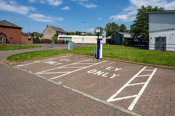 Empty parking space at EV charging station point in an urban area with white lines on ground