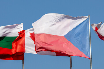 National flags flying on a flagpole, the Czech flag, the Canadian and Bulgarian flags in the background