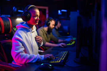 Focused gamer girl playing video games in internet cafe.