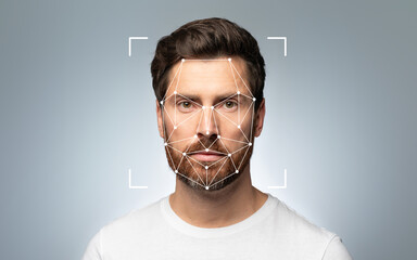 A bearded man stands front-facing with a facial recognition grid overlayed against a neutral backdrop.