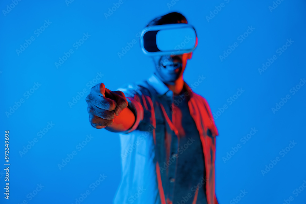 Aufkleber smiling gamer wear virtual reality glass while pointing at camera. happy caucasian man with vr goggl