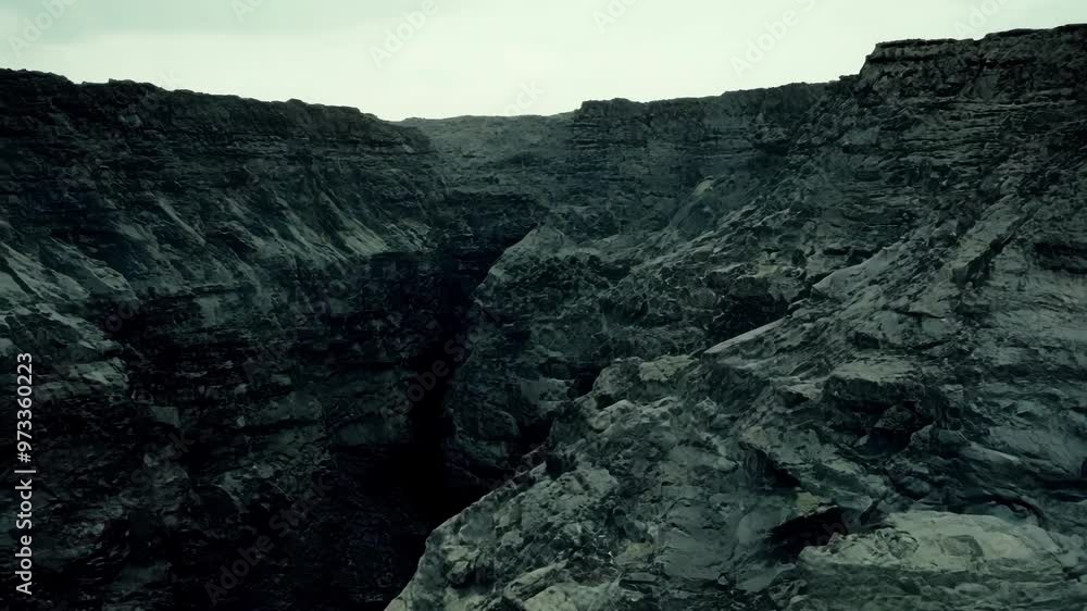 Aufkleber Dark green canyon with steep rocky cliffs stretching far away under a cloudy sky, creating a dramatic and mysterious atmosphere