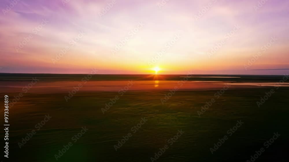 Poster The setting sun is casting long shadows across the landscape, creating a warm and inviting atmosphere. The vastness of the field evokes a sense of freedom and possibility