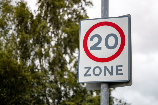 20mph speed limit restriction zone street sign on post with red circle road safety slow suburban traffic calming signage