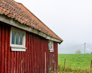 Red barn with uneven roof next to a field.