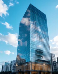 Obraz premium Modern Office Building with Glass Facade Reflecting Blue Sky and Clouds in Urban Skyline