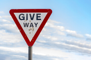 Give way warning red triangle sign with shotgun pellet holes