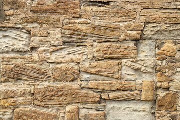 Yellow sandstone block and mortar wall with lamination lines and signs of wear and erosion stone...
