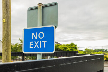 Car park blue No Exit sign on black metal gate to public road