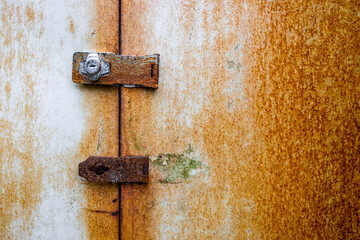 Closed rusty metal shed door with a clasp and lock which has a keyhole