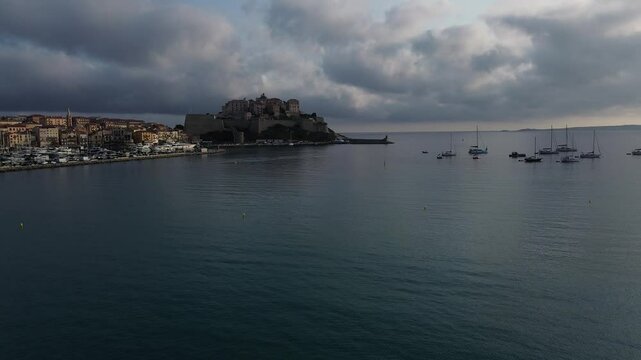 Sonnenaufgang  mit farbigen Wolken &uuml;ber der Stadt Calvi mit der historischen Zitadelle auf Korsika