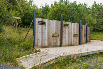 Wooden bird hide blind wall and accessible boardwalk with covered feeding station