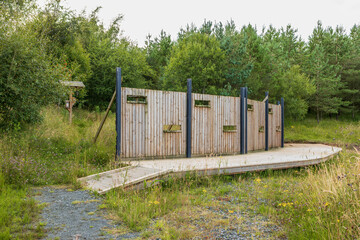 Wooden bird hide blind wall and accessible boardwalk with covered feeding station