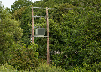 Electricity power transformer and two timber poles, transmission lines and insulators