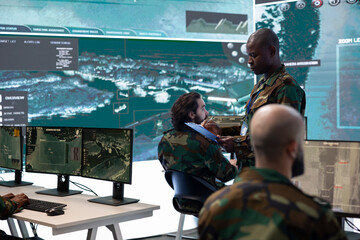 Commander and his squad operating satellite systems via CCTV and radar to track enemy aircraft or...