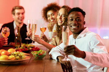 Happy New Year. Joyful Multiethnic Friends Celebrating Christmas Holiday Drinking Champagne Smiling To Camera During Dinner At Home. Selective Focus