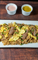 chaufa rice with chunks of meat, accompanied by homemade creams.