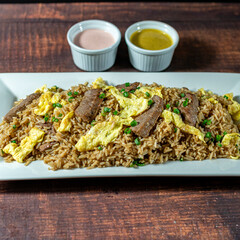 chaufa rice with chunks of meat, accompanied by homemade creams.