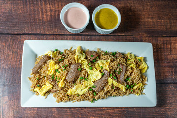 chaufa rice with chunks of meat, accompanied by homemade creams.