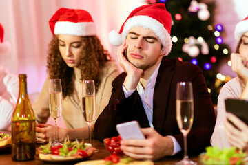 Dull Christmas Party. Bored Millennial Couple Using Phones During Boring New Year Celebration With...