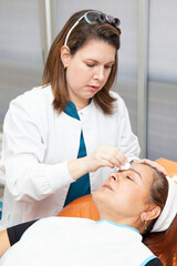 Fototapeta premium Dermatologist preparing a middle age female patient for botulinum toxin application. Aesthetic medicine