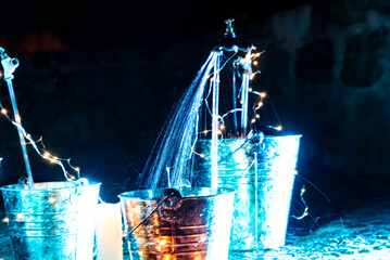 optical effect of water jets on illuminated metal cubes in the garden. traces in the water and selective blur.