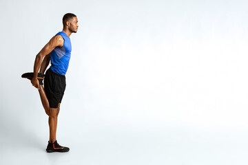 Warm Up. Side view of black man stretching legs before run over yellow studio wall, full length, copyspace
