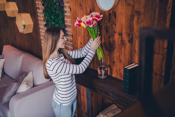 Photo of nice young girl put flowers vase wear striped pullover loft interior apartment indoors
