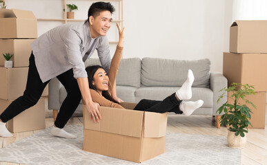 Home, People, Moving And Real Estate Concept. Excited asian couple having fun and riding in...
