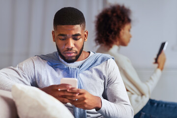 Indifference in relationships. Black couple using cellphones and ignoring one another
