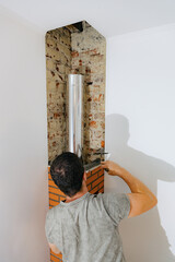 A young man makes brickwork on the chimney of a fireplace.