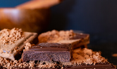 Close-up of dark chocolate pieces and cocoa powder on dark background.