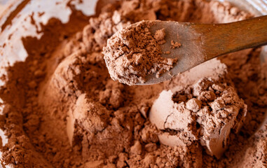 Close-up photo of natural textured cocoa powder on wooden spoon.