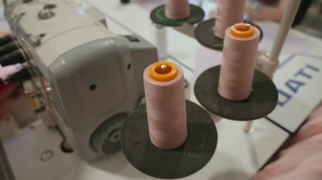 A close-up of a spool of thread. Clothing production. Thread from spool is wound onto a bobbin in sewing machine. Tailoring, thread unrolling from reel. High quality 4k footage