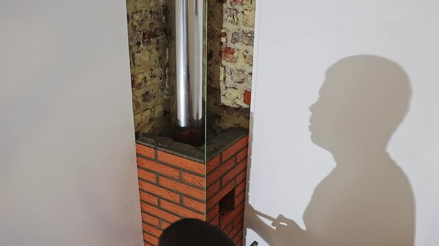 One young handsome man, a builder of the Caucasian race, removes two thin planks from the freshly applied cement mortar from the bricks of the fireplace smoker and carefully examines the quality of th