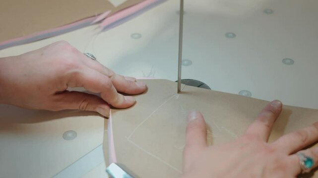 Close-up of a woman's hands making a professional cut of fabric with a cutting machine. Textile factory, garment production and new technologies. High quality 4k footage