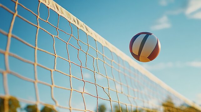 A volleyball soaring over a net against a clear blue sky.