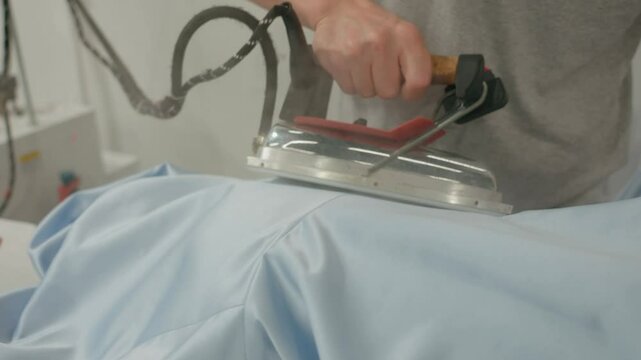 Close-up view of a female worker ironing clothes. Dry cleaner, laundry, industrial factory, clothing production. Professional steaming of clothes.Tailoring production. . High quality 4k footage
