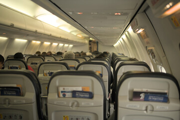 Back view of an airplane seats with few passengers.