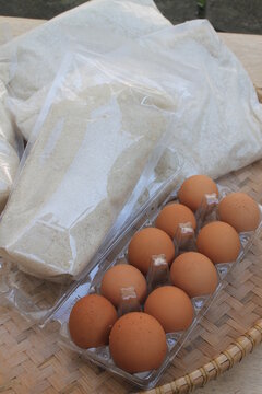 Rice, sugar and eggs in woven bamboo called tampah on a wooden table


