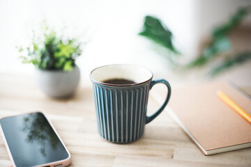 木製テーブルに置かれたコーヒーとスマホ