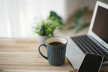 開いたノートパソコンとスマホとコーヒー