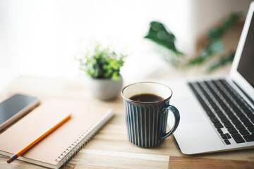 開いたノートパソコンと筆記用具とコーヒー