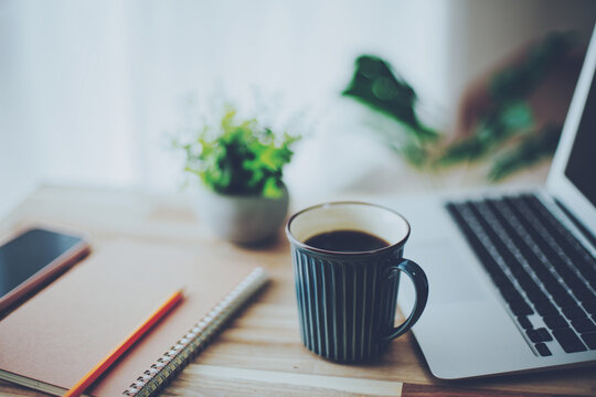 開いたノートパソコンと筆記用具とコーヒー