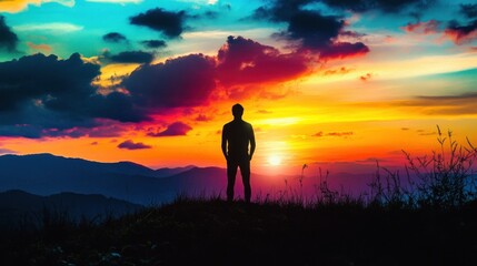 Obraz premium A man finding inner peace while watching a sunset from a hilltop, his silhouette against a colorful sky