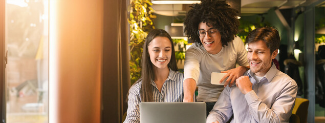 Three young multiethnic professionals engage in a collaborative work session at a cozy cafe,...
