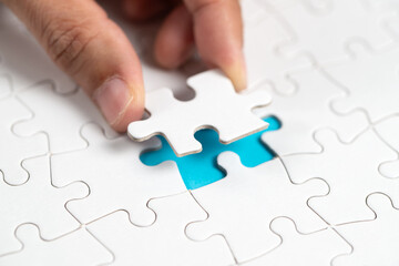 Hand put the last piece of jigsaw puzzle to complete the mission