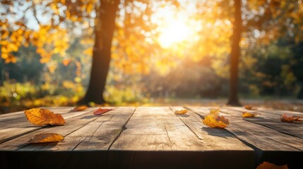Wooden table with autumn leaves in a blurry background of trees and sunlight.