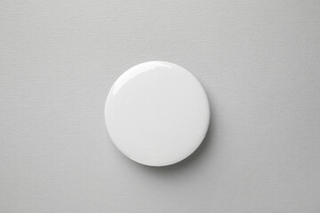 Blank white button badge on grey background, top view. Mockup for design