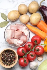 Uncooked ingredients for stew on white marble table, flat lay